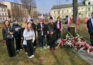 Uczniowie klasy VIb stoją przy pomniku Polaków ratujących Żydów.