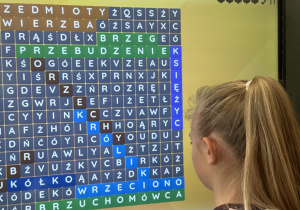 Uczennica rozwiązuje zagadki ortograficzne na tablicy.