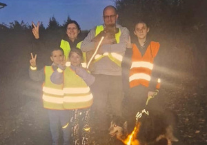 Zdjęcie, które zdobyło II miejsce- rodzice oraz trójka dzieci i pies w kamizelkach po zmierzchu.