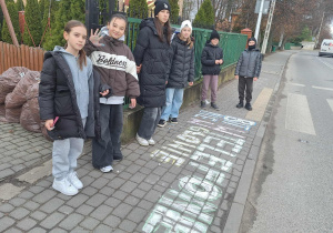 Uczniowie klasy Va stoją na chodniku przy szkole.