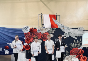 Nagrodzeni w konkursie polonistycznym stoją z dyplomami i nagrodami.