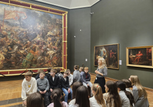 Uczniowie klas piątych siedzą w Muzeum Narodowym podczas warsztatów.