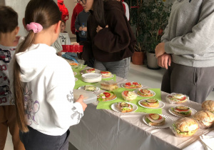Dziewczyny z klasy VIIIb sprzedają kanapki młodszym dzieciom.