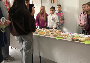 Uczniowie wybierają kanapki na stoisku.
