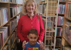 Franek stoi z wychowawcą pomiędzy regałami z książkami w bibliotece.