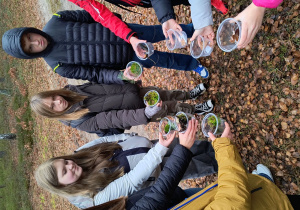 Uczniowie prezentują skarby zebrane w lesie.