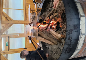 Dzieci pieką kiełbasę przy ognisku.