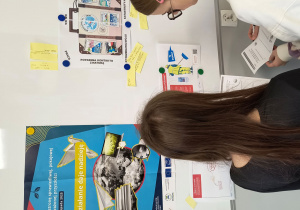 Dziewczynki odczytują zadania ze ściany.