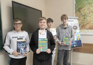 Wyróżnieni chłopcy stoją z nagrodami i dyplomami.