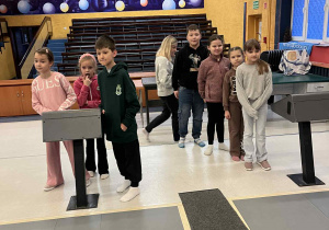 Dzieci stoją w szeregu przy torach w kręgielni.