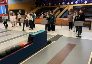 Uczniowie podzieleni na drużyny czekają przy torach na rozpoczęcie zabawy.