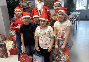Dzieci z klasy IIIb stoją z Mikołajem i prezentami od niego.
