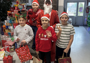 Troje uczniów klasy IIIa stoi obok Mikołaja z prezentami.