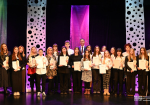 Pani A. Kujawska, p. E. Turlik- Kostanek i uczennica K. Bieganowska stoją wśród nagrodzonych ze statuetkami na scenie