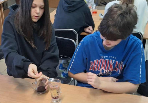 Dziewczyny mieszają w szklance różne substancje.