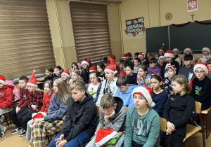 Uczniowie klas czwartych i piątych siedzą i słuchają fragmentów " Opowieści z Narnii".