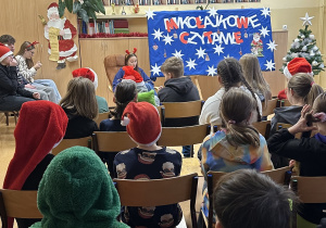 Uczniowie słuchają, jak koleżanka z klasy VIIIa czyta fragmenty książki " Opowieści z Narnii"