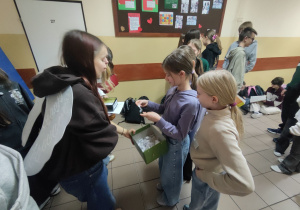 Dziewczynki z klasy IVb losują z pudełka wyzwania do wykonania dobrych uczynków.