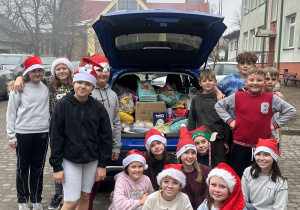 Uczniowie przy samochodzie wypełnionym darami dla schroniska.