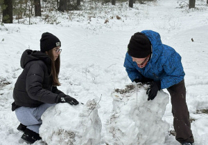 Dziewczyna i chłopak lepią bałwana.