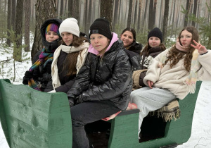 Dziewczynki siedzą w saniach.