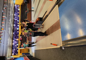 Dzieci stoją przy torze w kręgielni.