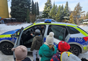 Dzieci oglądają policyjny radiowóz.