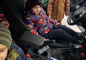 Dzieci z grupy "0" siedzą w policyjnym radiowozie.