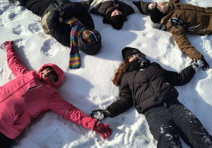 Dzieci leżą na śniegu.