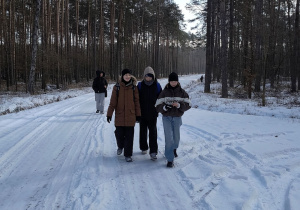 Uczniowie idą przez las.