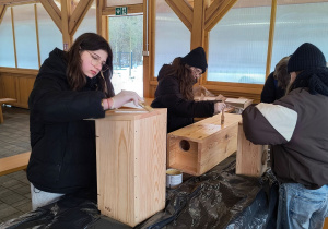 Dziewczynki malują budki dla ptaków.