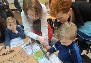 Dzieci z rodzicami bawią się długopisami 3D.