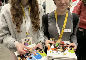 Dziewczynki trzymają komplet materiałów festiwalowych.