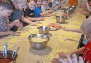 Dzieci przygotowują ciasto na pizzę.