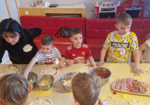 Przedszkolaki kładą produkty na swoje pizze.