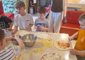 Chłopcy przygotowują pizze.
