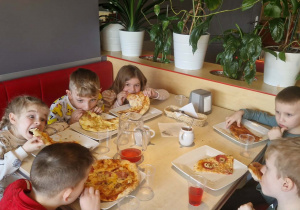 Dzieci jedzą pizzę.