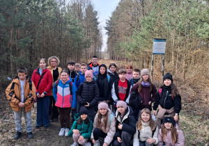 Uczniowie klasy IVb z wychowawcą na trasie rajdu w lesie.