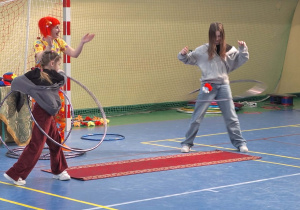 Dziewczynki próbują kręcić kołami hula hop.