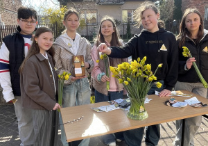 Starsi wolontariusze stoją przed kościołem z kwiatami.