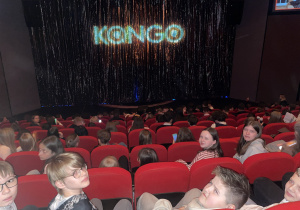 Szóstoklasiści siedzą na widowni w teatrze.