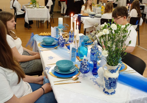 Uczniowie z drużyny na 1 siedzą przy stole przygotowanym do konkursu.