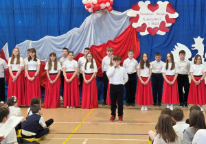 Uczeń klasy Vb stoi z klasą i wita na uroczystości.