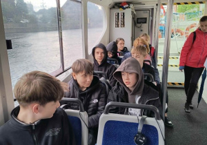 Uczniowie siedzą w tramwaju wodnym podczas rejsu.