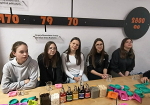 Dziewczyny siedzą przy stole przed warsztatami tworzenia mydełek.