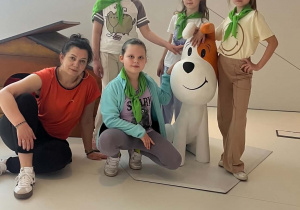 Dziewczynki z wychowawcą obok figurki psa Reksia