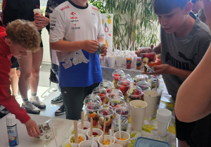 Uczniowie kupują owoce w kubeczkach.
