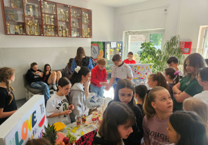 Dzieci kupują sałatki owocowe w kubeczkach.