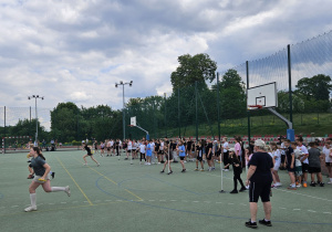 Uczniowie wykonują konkurencje sportowe na biosku.