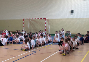 Uczniowie klas I- III siedzą w hali sportowej.